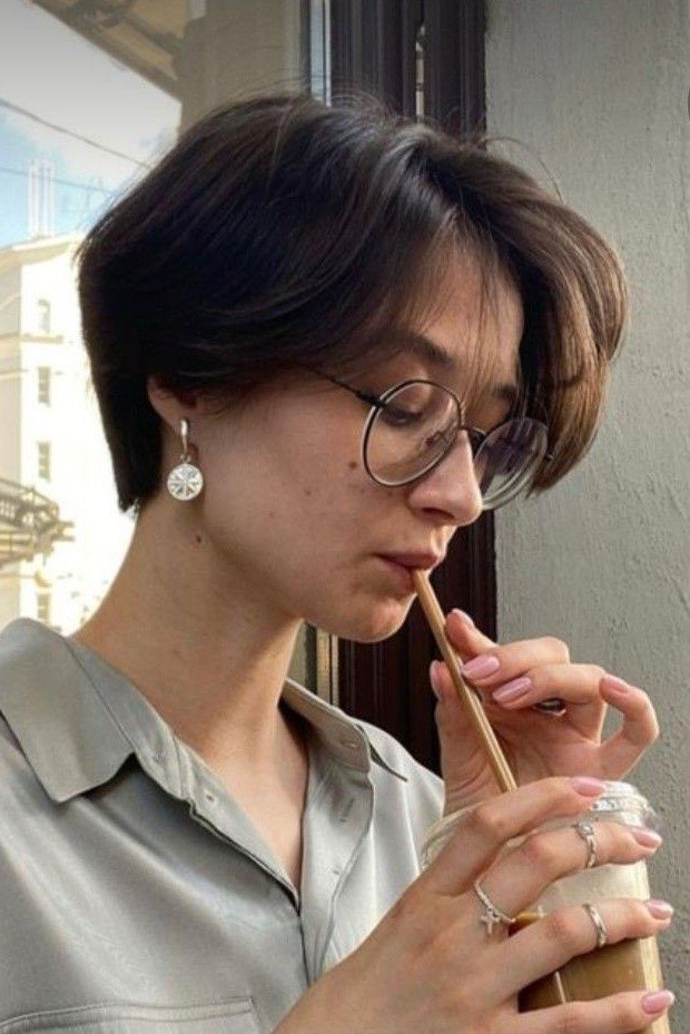 14. Smooth Dark Brown Classic Pixie Cut with Long Side Bangs and Glasses
