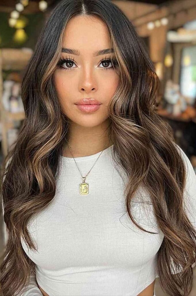 11. Long Wavy Brunette Hair with Soft Caramel Face-Framing Highlights