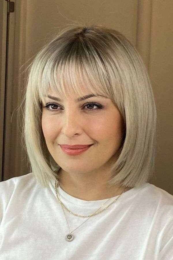 18. Sleek Platinum Blonde Blunt Lob with Wispy Straight Bangs