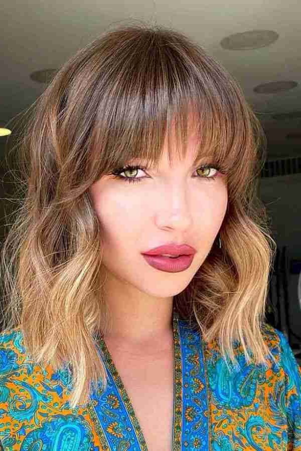 19. Honey-Toned Wavy Lob with Heavy Straight-Across Bangs