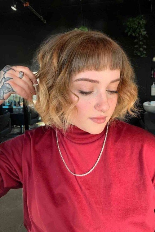 19. Wavy Warm Blonde French Bob with Short Micro Fringe