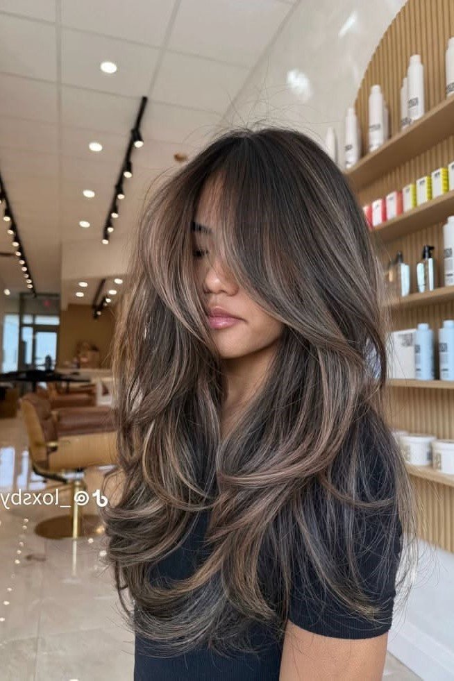 6. Voluminous Layered Brunette Hair with Taupe Tone-on-Tone Balayage and Curtain Bangs