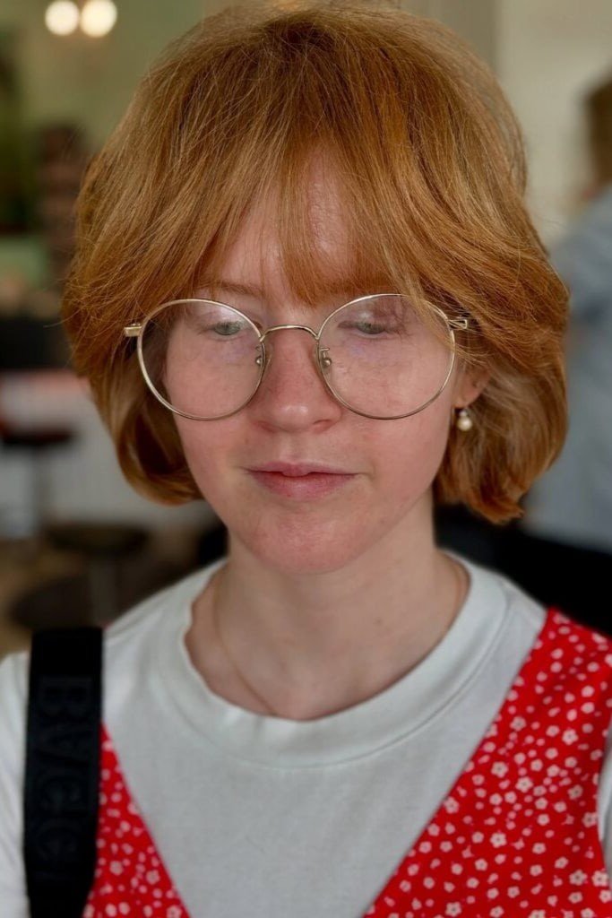 5. Voluminous Copper Red Rounded Cut with Thick Sweeping Bangs